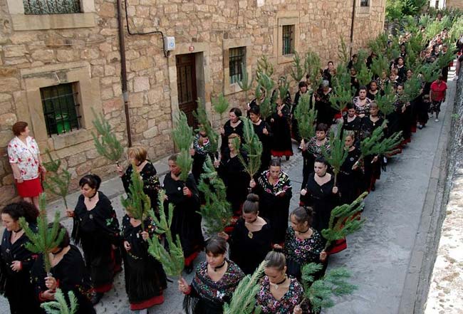 Las mujeres portan ramas de pino